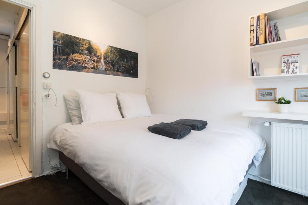 Un dormitorio con una cama blanca con una foto en la pared en Vondel Park Studio, en Ámsterdam