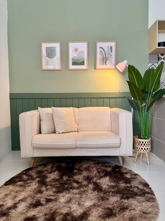 a living room with a white couch and a plant at Studio Inap Seri Iskandar in Kampong Bota Road