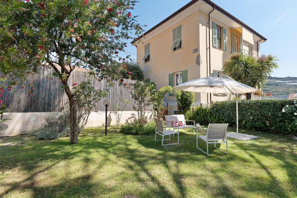 a house with a table and chairs and an umbrella at Casa Lena in Arma di Taggia