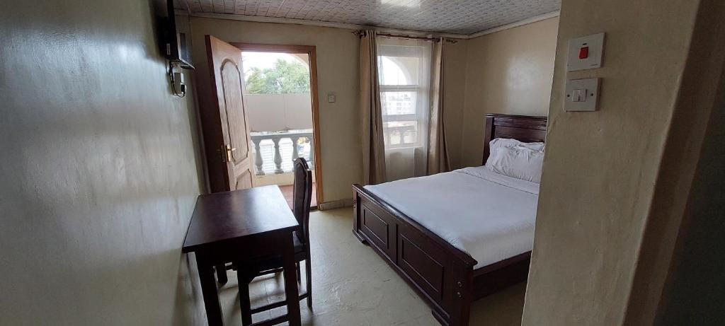 a bedroom with a bed and a table and a window at Crown Accommodation Narok in Narok