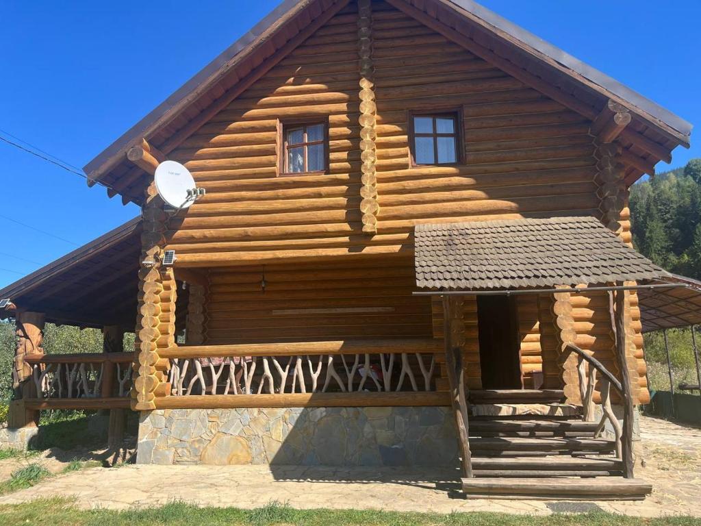 a log cabin with a porch and a balcony at Думанія in Verkhovyna