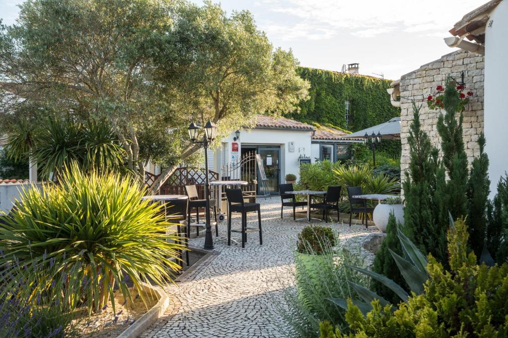 a garden with a table and chairs and plants at Hôtel Le Peu Breton in Sainte-Marie-de-Ré