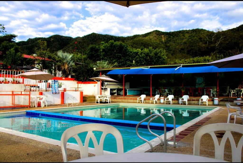 a swimming pool with chairs and tables and a building at La melosa in Girardot
