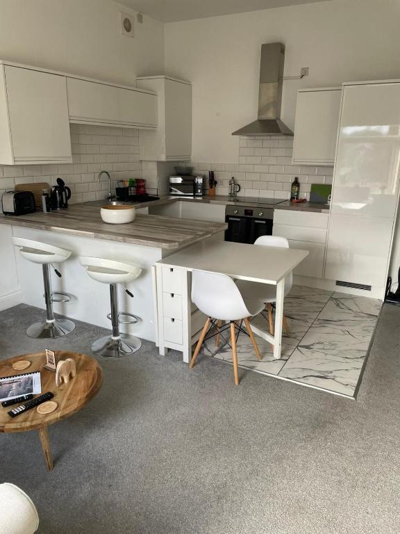 a kitchen with a table and some chairs in it at 2 bed- walkable train and beach apartment in Crosby