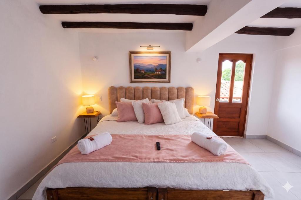 a bedroom with a large bed with pink pillows at Casa Hotel La Morada in Villa de Leyva