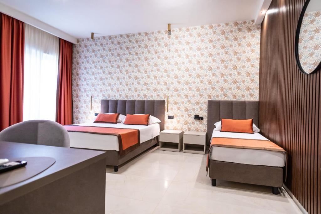 a hotel room with two beds and a desk at Ambrosia Room & Apartment in Rossano