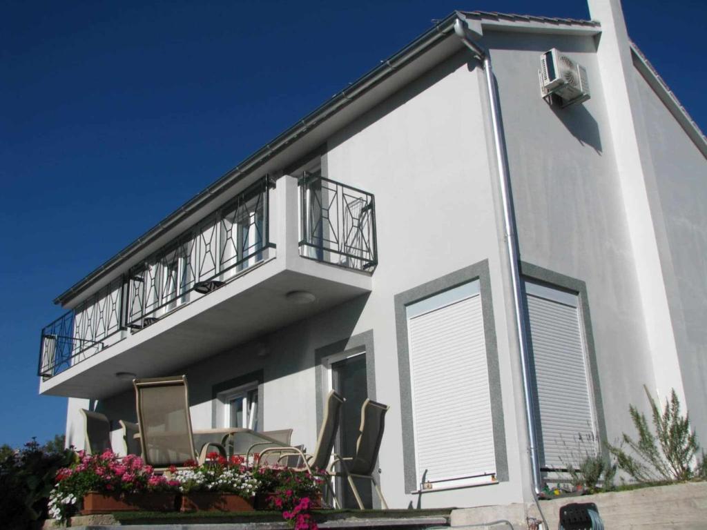 a white building with a balcony with chairs on it at Slanraj apartman in Jadrtovac