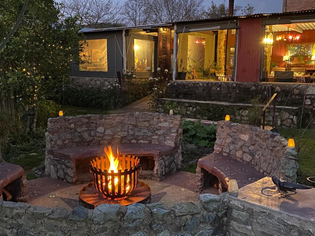 a fire pit in a yard with benches and a house at Bohemian Garden Cottages in Kaapsehoop