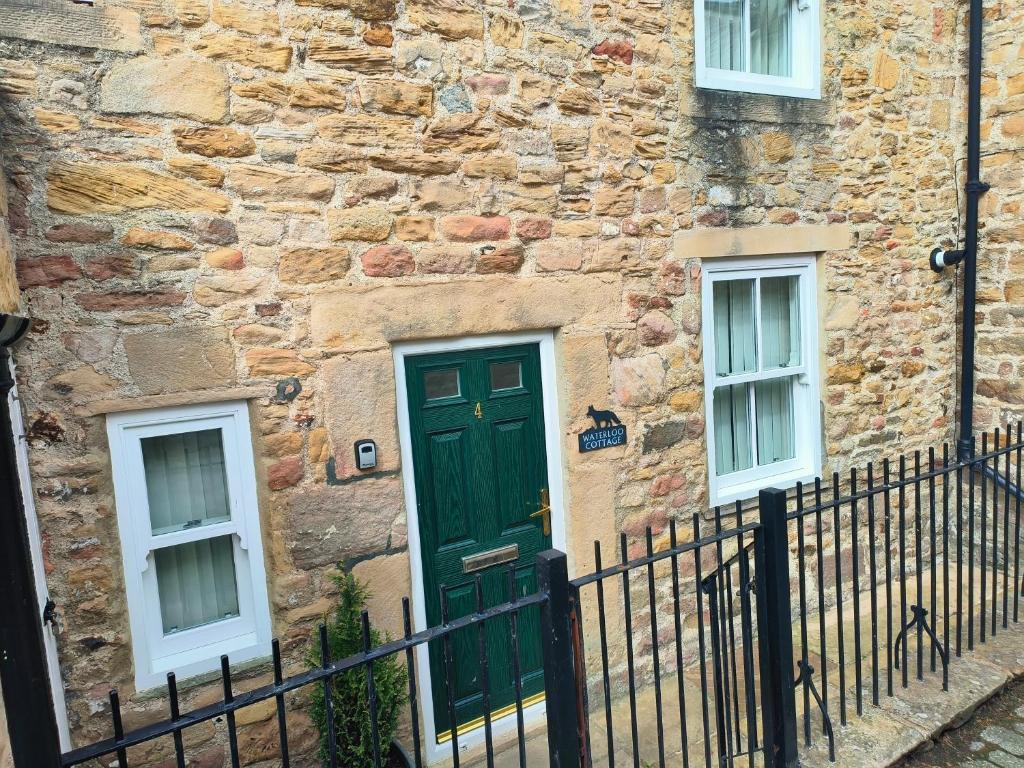 a green door on the side of a stone building at Waterloo Cottage in Barnard Castle