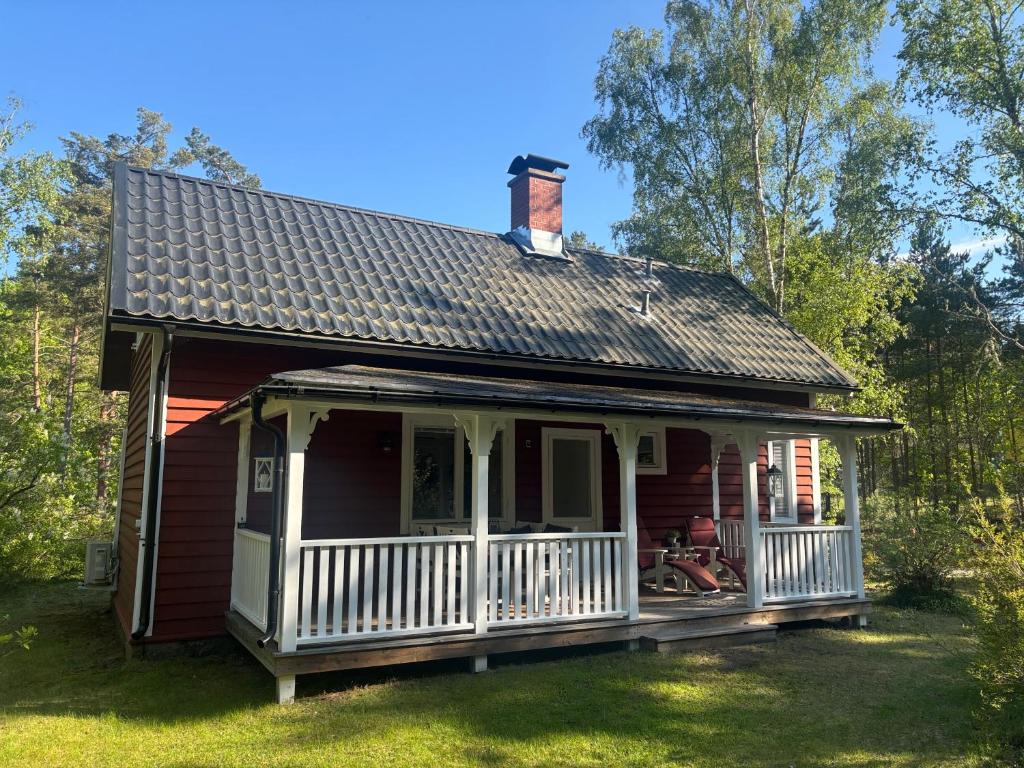 a small red house with a white porch at Banvaktstuga anno 1905 in Fliseryd
