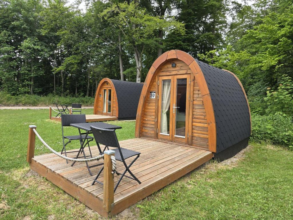 a small wooden cabin with a table and chairs on a deck at 39 Mini Pod "Treene" in Silberstedt