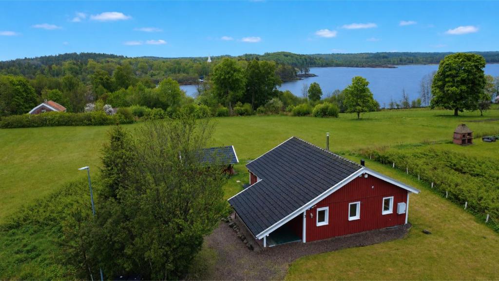 a red barn in a field next to a lake at Hus Kalvsjö in Kalv