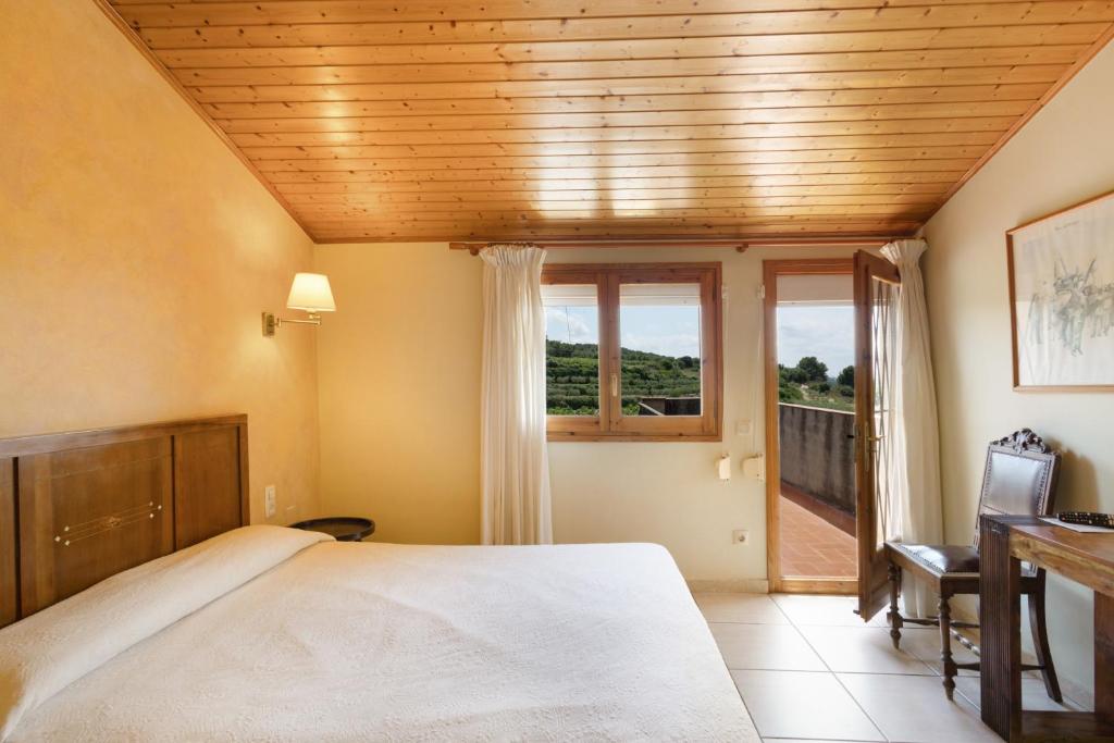 a bedroom with a bed and a desk and a window at Ball de Diables in Sant Pau dʼOrdal
