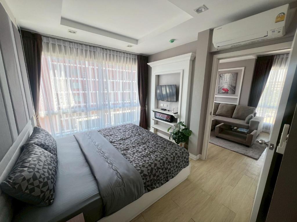 a bedroom with a bed and a couch and a window at The Patio Bangsaen Cozy Condo in Chon Buri