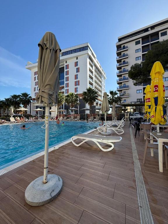 a pool with chairs and umbrellas next to a swimming pool at Sea & Mount apartament in Shëngjin