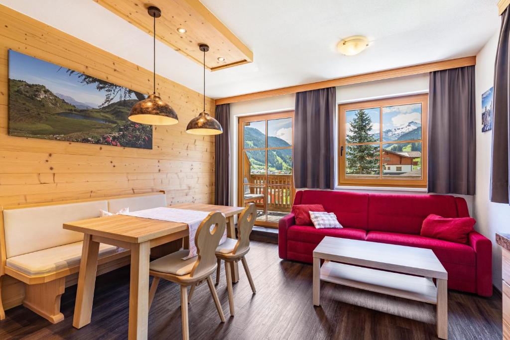 a living room with a red couch and a table at Appartements Stockinger A1 in Grossarl