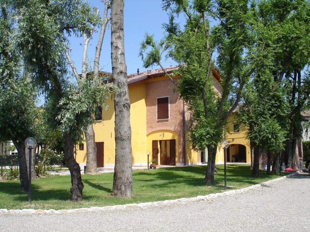 モデナにあるFondo Giardinettoの目の前の木々が茂る黄色い家