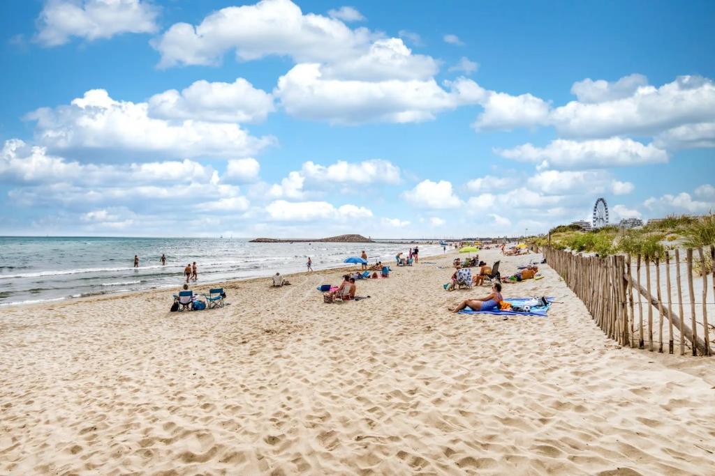 a group of people sitting on the beach at Le Murmure des palmiers in La Grande Motte