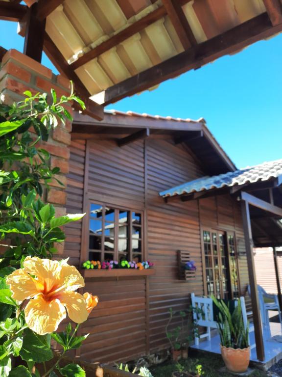 a wooden house with a flower in front of it at Chalés da Sinhá in Penha