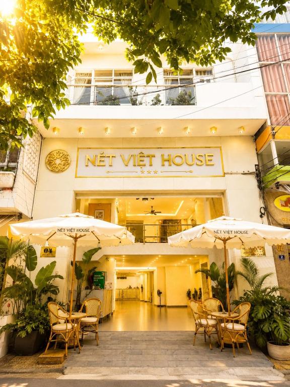 a not yet house with tables and umbrellas in front of it at Nét Việt House Hotel Market & Bridge Centre Soc Trang in Soc Trang