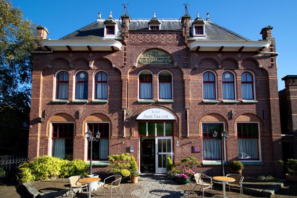 een bakstenen gebouw met tafels en stoelen ervoor bij Hotel Saint Vincent in Poeldijk