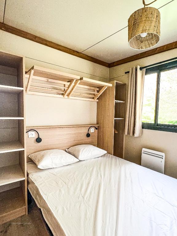 a small bedroom with a bed and shelves at Camping Onlycamp Au Cœur du Lac - Lac d'Annecy in Sévrier