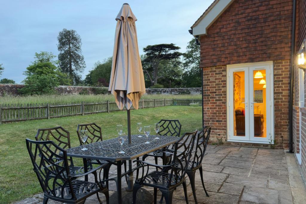 a table and chairs with an umbrella on a patio at Walled garden cottage in Hassocks