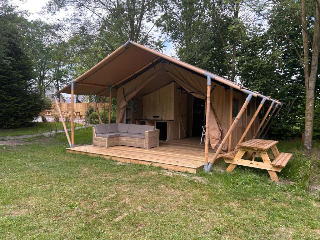 a tent with a table and a bench in a field at Minicamping Het Zuiderscheveld in Hollandscheveld