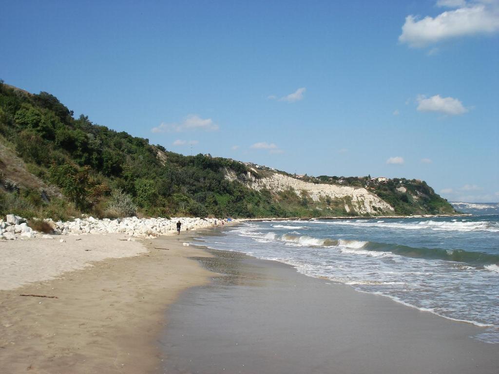 a sandy beach with a mountain and the ocean at Villa Exotica in Balchik