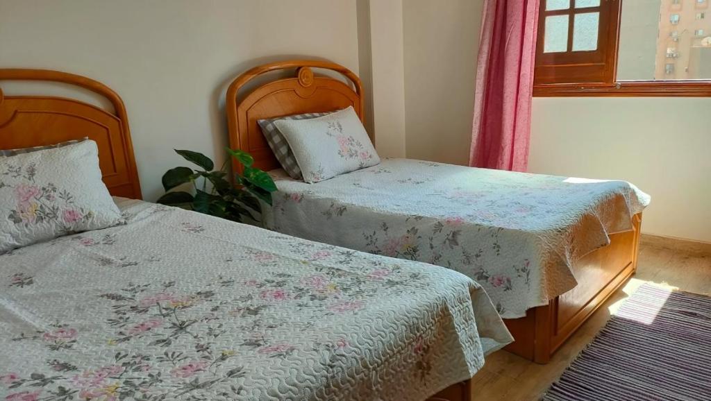 a bedroom with two beds and a window at 378 Pyramids apartment in Nazlet el-Sîsi