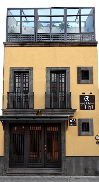 a tall yellow building with windows and a balcony at Casa Tita in Acámbaro