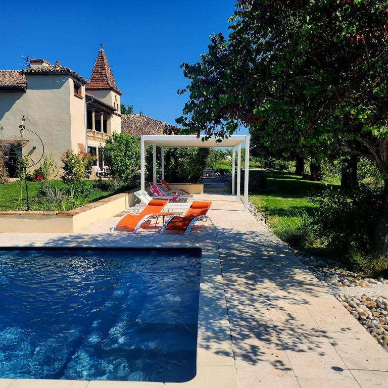 a swimming pool with orange chairs next to a house at Aux Coteaux d'Aussac in L Honor De Cos