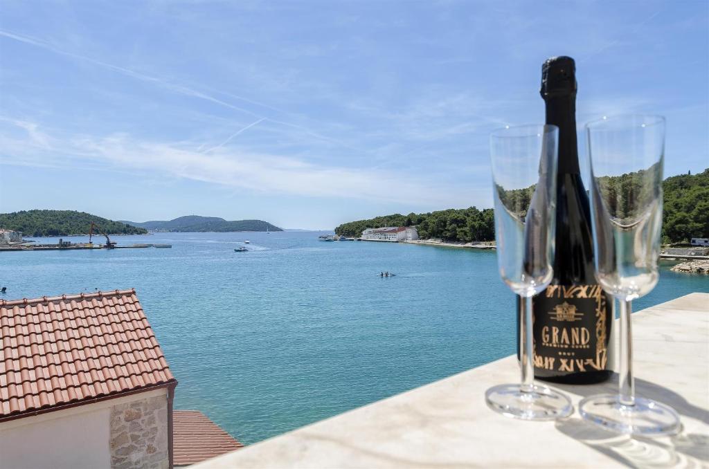 two wine glasses sitting on a table with a view of the water at Apartment Mirni by the sea in Prvić Luka