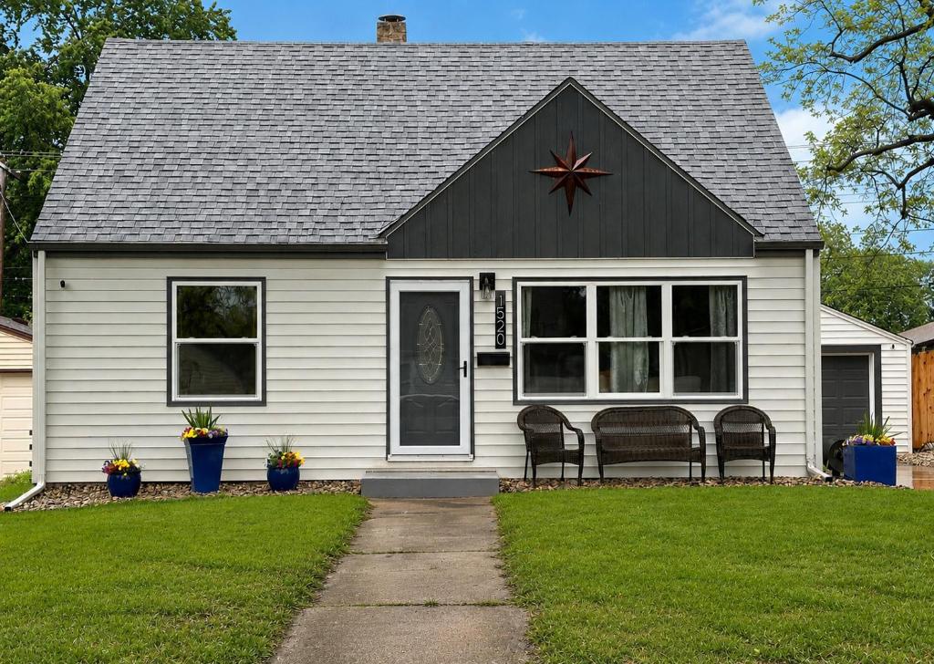 a white house with two chairs in the front yard at Serenity Landing in Sioux Falls