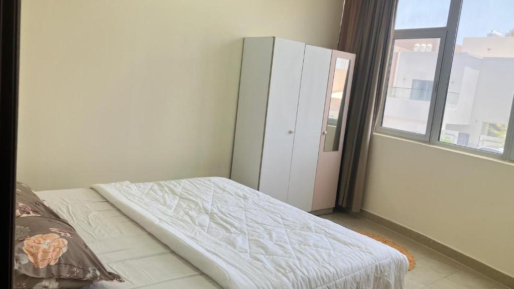 a bedroom with a bed and a cabinet and a window at Alsayah in Jazīrat as Sāyah
