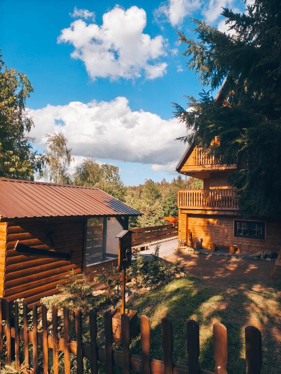 a log cabin with a fence next to a building at Chata Sovička in Kokava na Rimavica