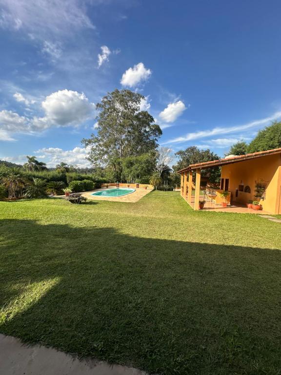 a large yard with a swimming pool and a house at Chácara porta do sol in Mairinque