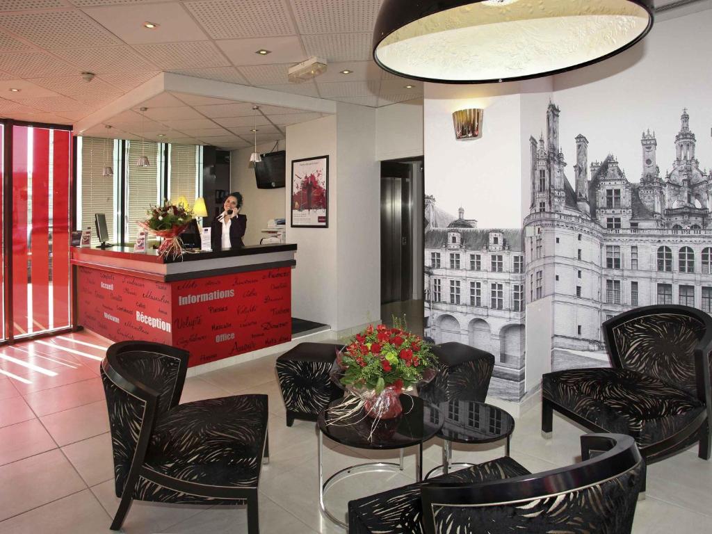 a woman is standing at a cash register in a lobby at Mercure Tours Centre Gare et Congrès in Tours