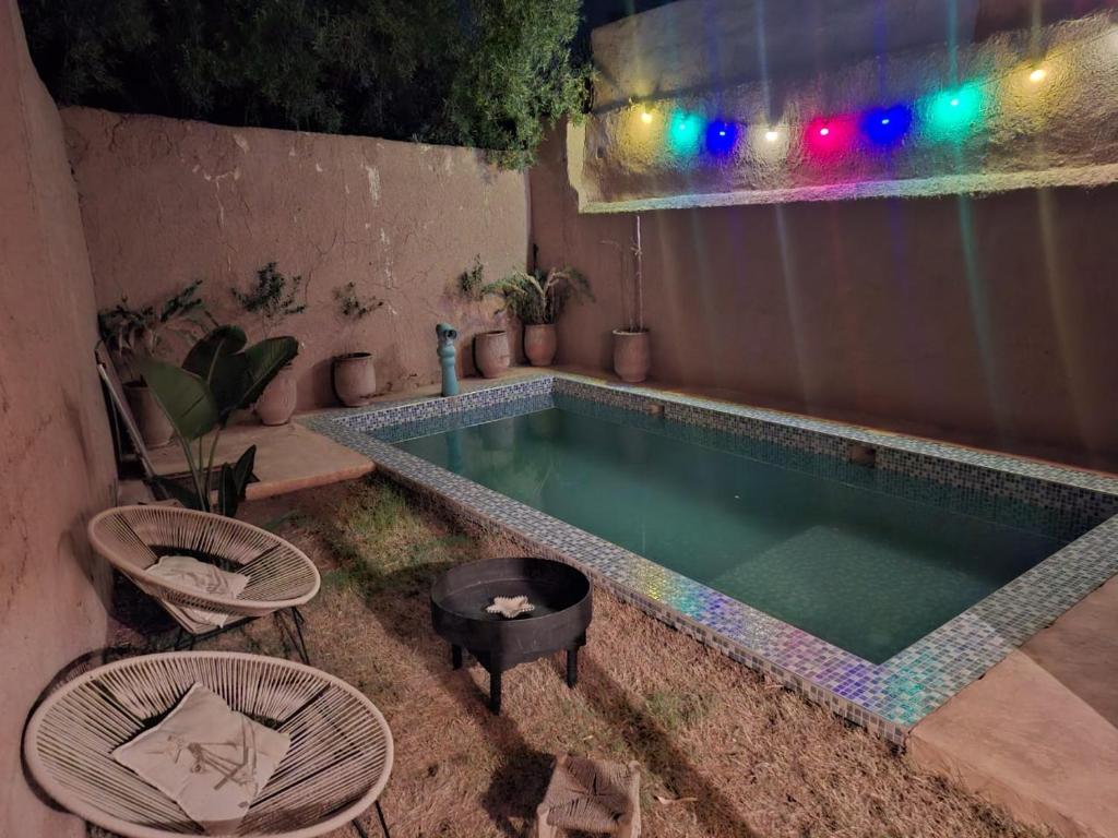 a swimming pool with two chairs and a tub at Gîte berbère in Tagadirt Alkadi