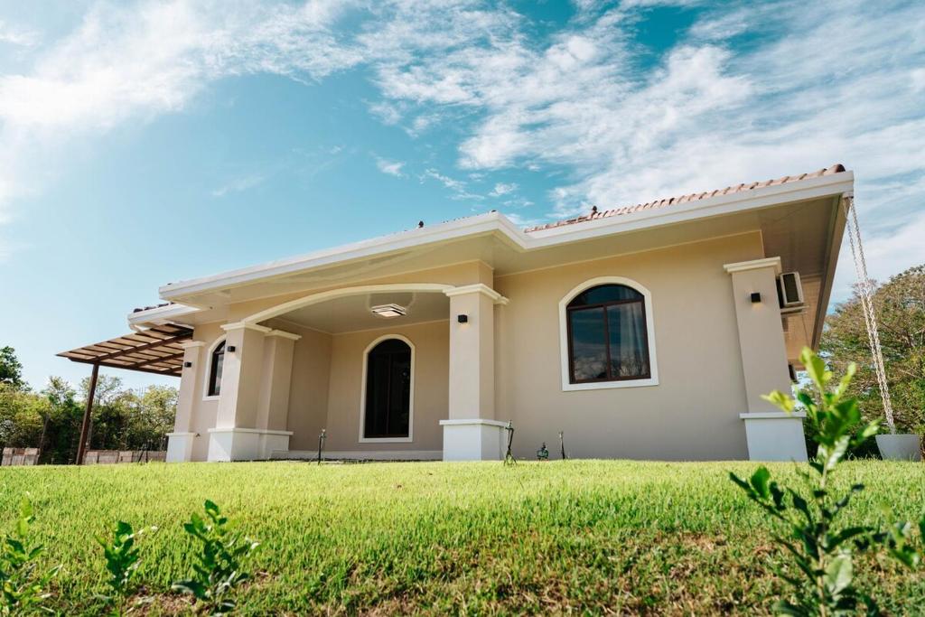 a small house with a green lawn in front of it at Pedasi, Casa Limon - 2 BD in Purio