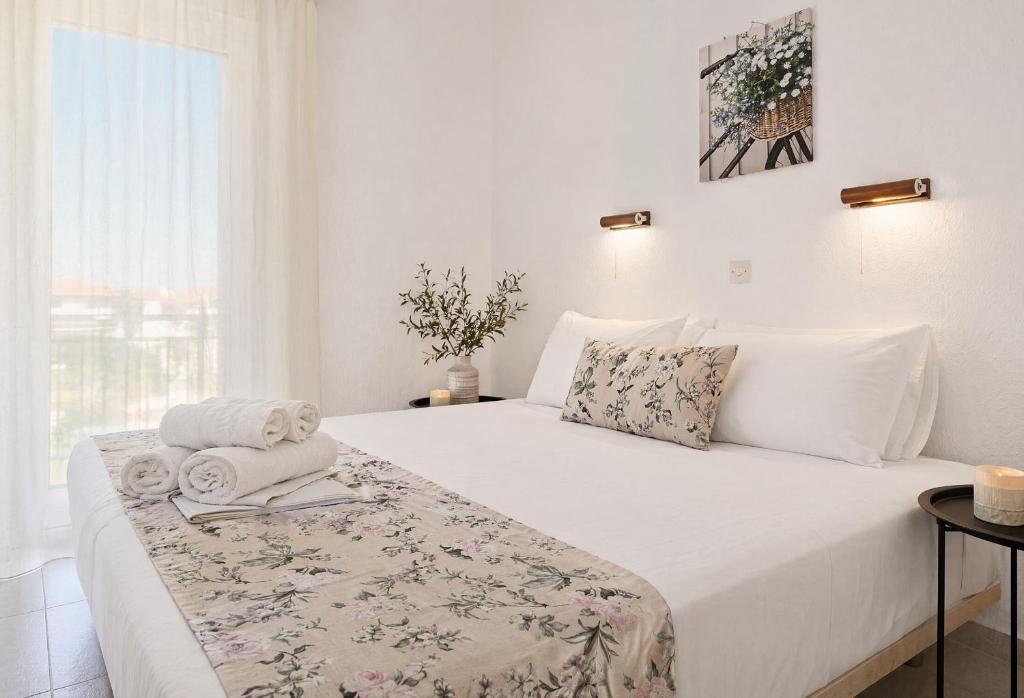 a white bedroom with a bed with towels on it at H Stella Apartments & Rooms in Kalamitsi
