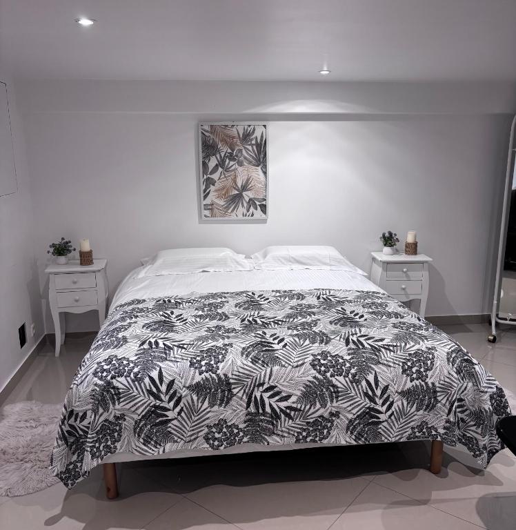 a bedroom with a bed with a black and white comforter at Appartement Carreira in LʼIsle-Adam