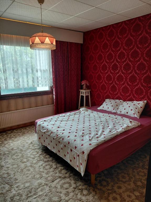 a bedroom with a bed with a red wall at Guest room in Retro House in Turku