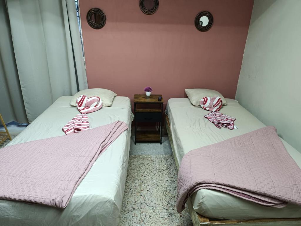 two beds in a room with pink walls at Jayua Suites & Habitaciones in Córdoba