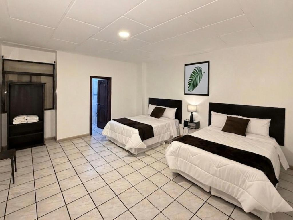a bedroom with two beds and a tiled floor at Hotel NASS del Sur in Cuenca
