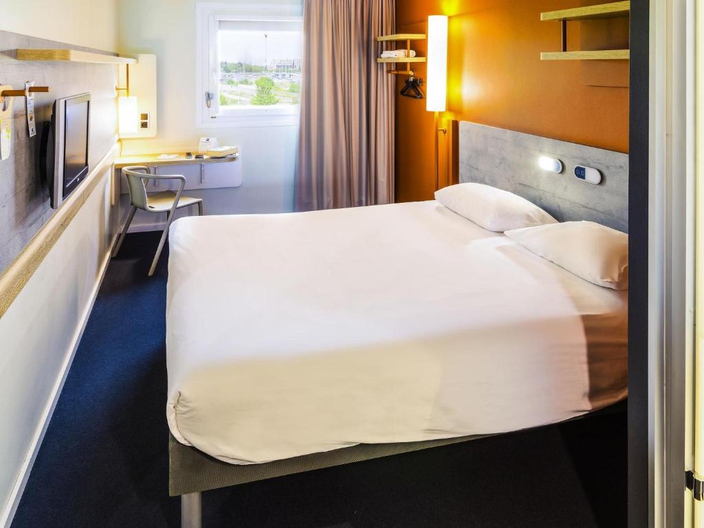 a hotel room with a large bed and a desk at ibis Budget Luxembourg Aeroport in Luxembourg