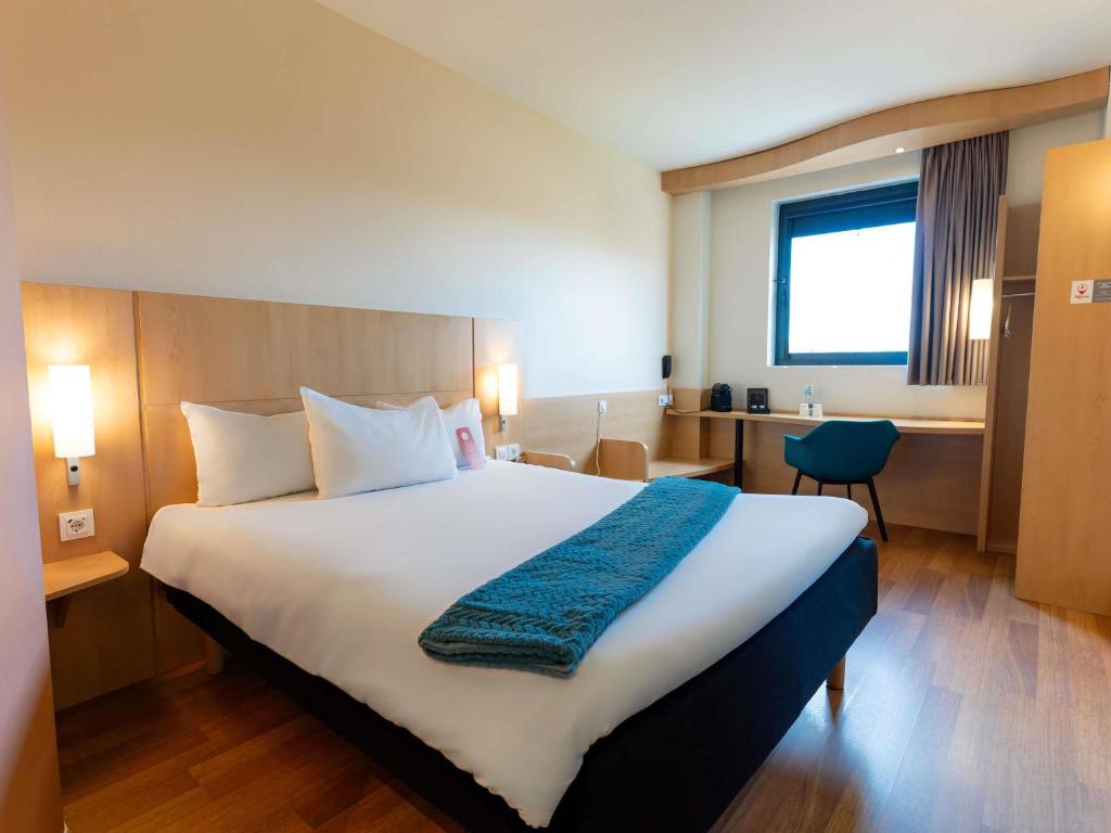 a hotel room with a large bed and a desk at Ibis Ripollet in Ripollet