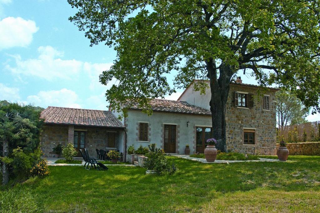 a stone house with a tree in the yard at Agriturismo Casa Fibbianello in Semproniano