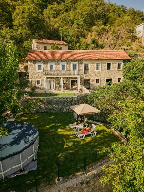a house with two chairs and an umbrella in front of it at Apartmani Stone oasis in Zupci