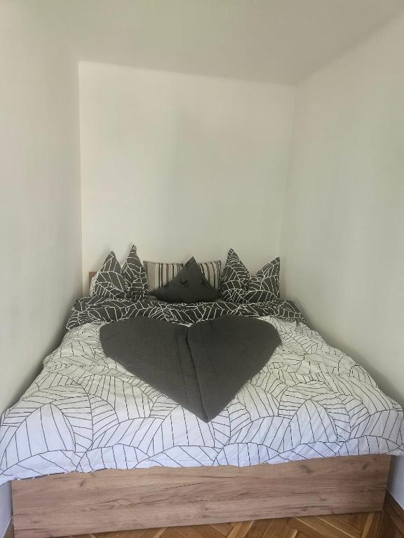 a bed with a black and white comforter and pillows at Sweet Escape Pécs in Pécs
